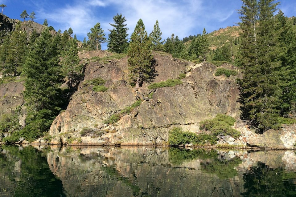 Un lac paisible, bordé de falaises rocheuses et entouré de forêts denses.