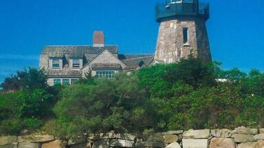 A lighthouse and a stone house on a cliff by the sea.