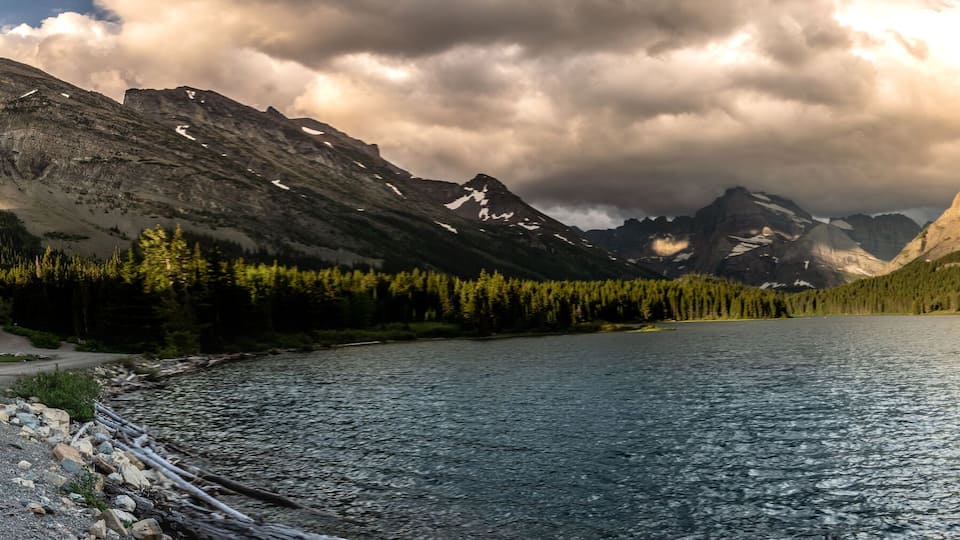 A mountain peak surrounded by a lake and forest.