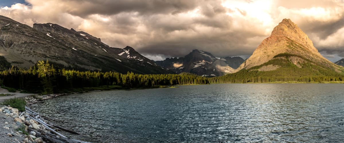 A mountain peak surrounded by a lake and forest.