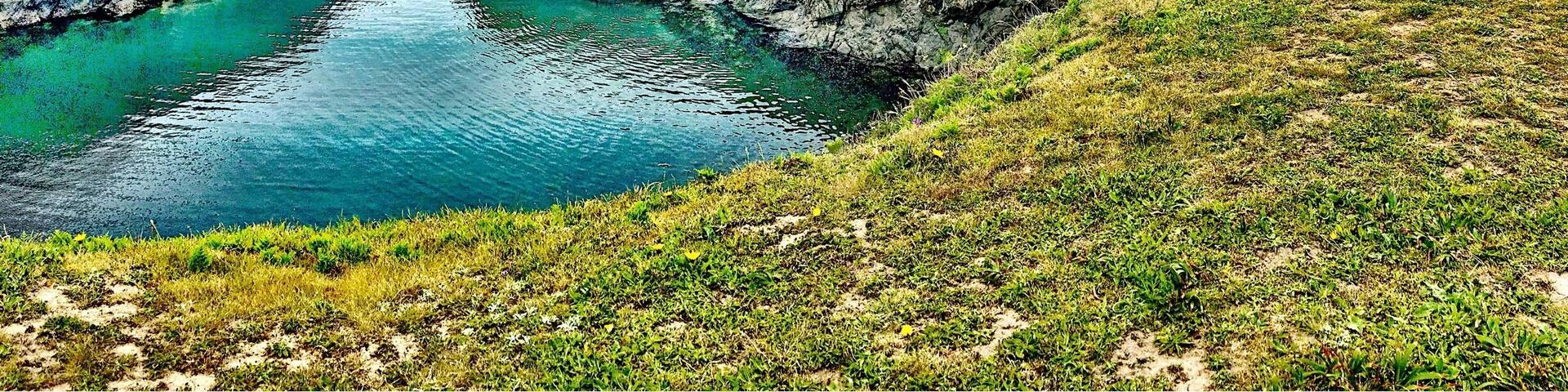 Un faro en un acantilado cubierto de hierba que domina un estrecho canal.