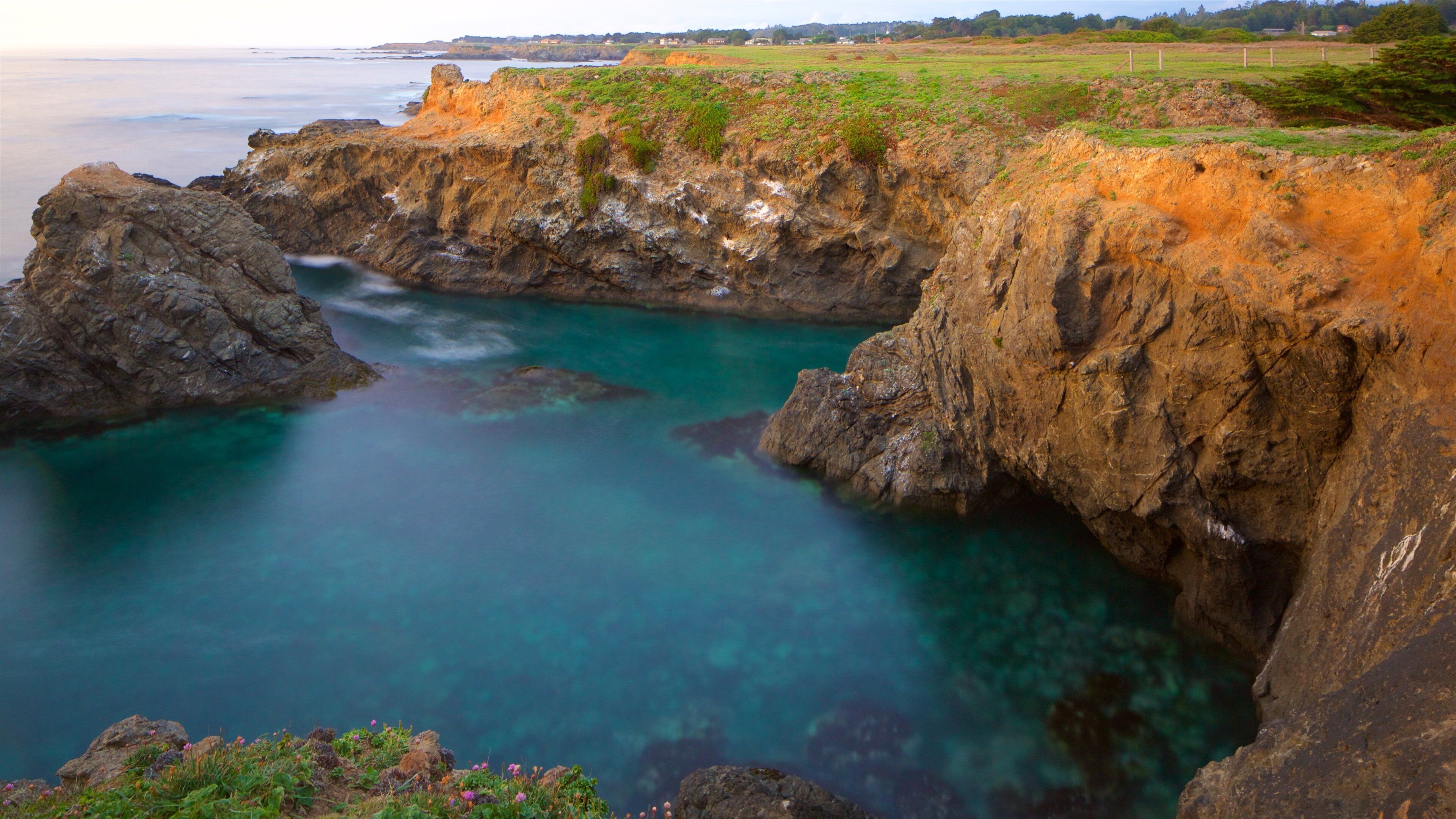 A coastal landscape with rocky cliffs and clear turquoise waters.