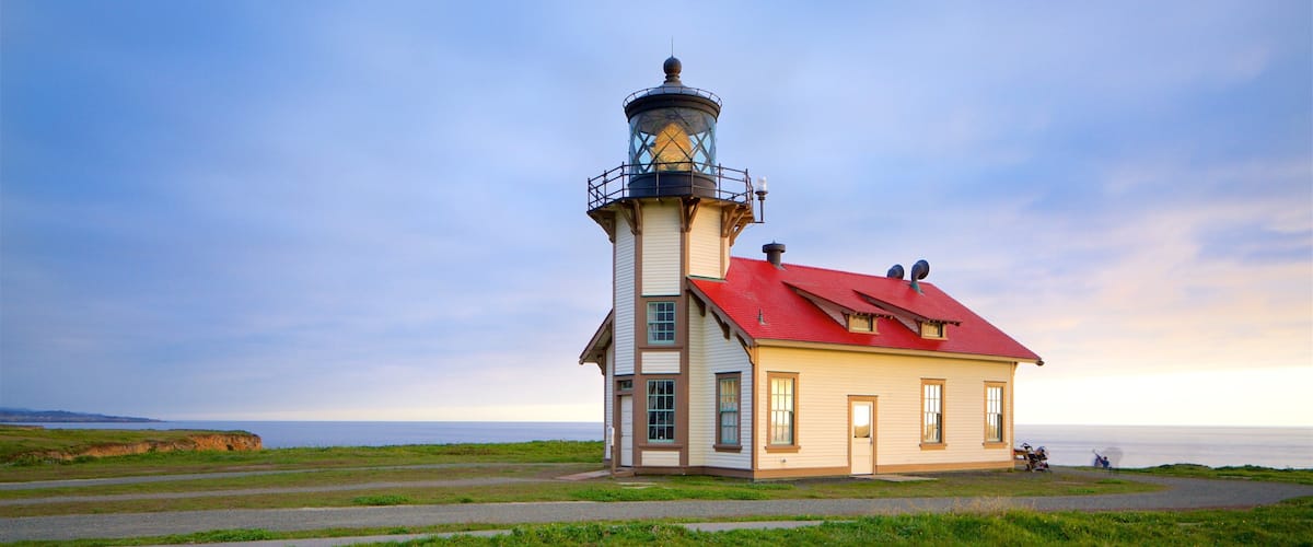A lighthouse with a red roof and a white building next to it.