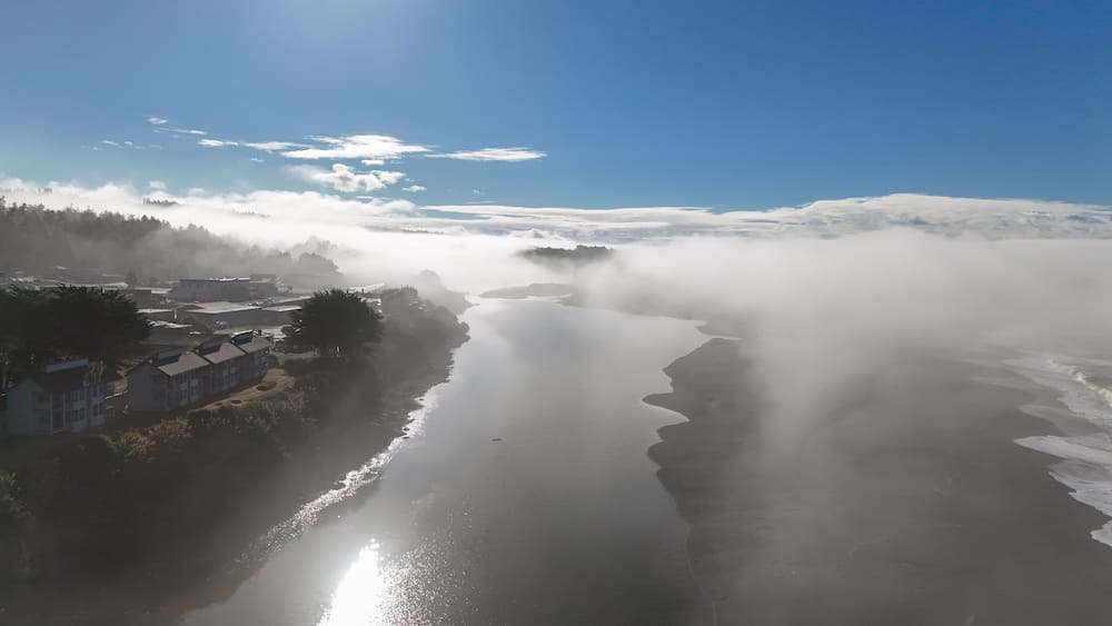 Aerial view of serene coastal fog over a tranquil river and lush trees, Gualala, California, United States.