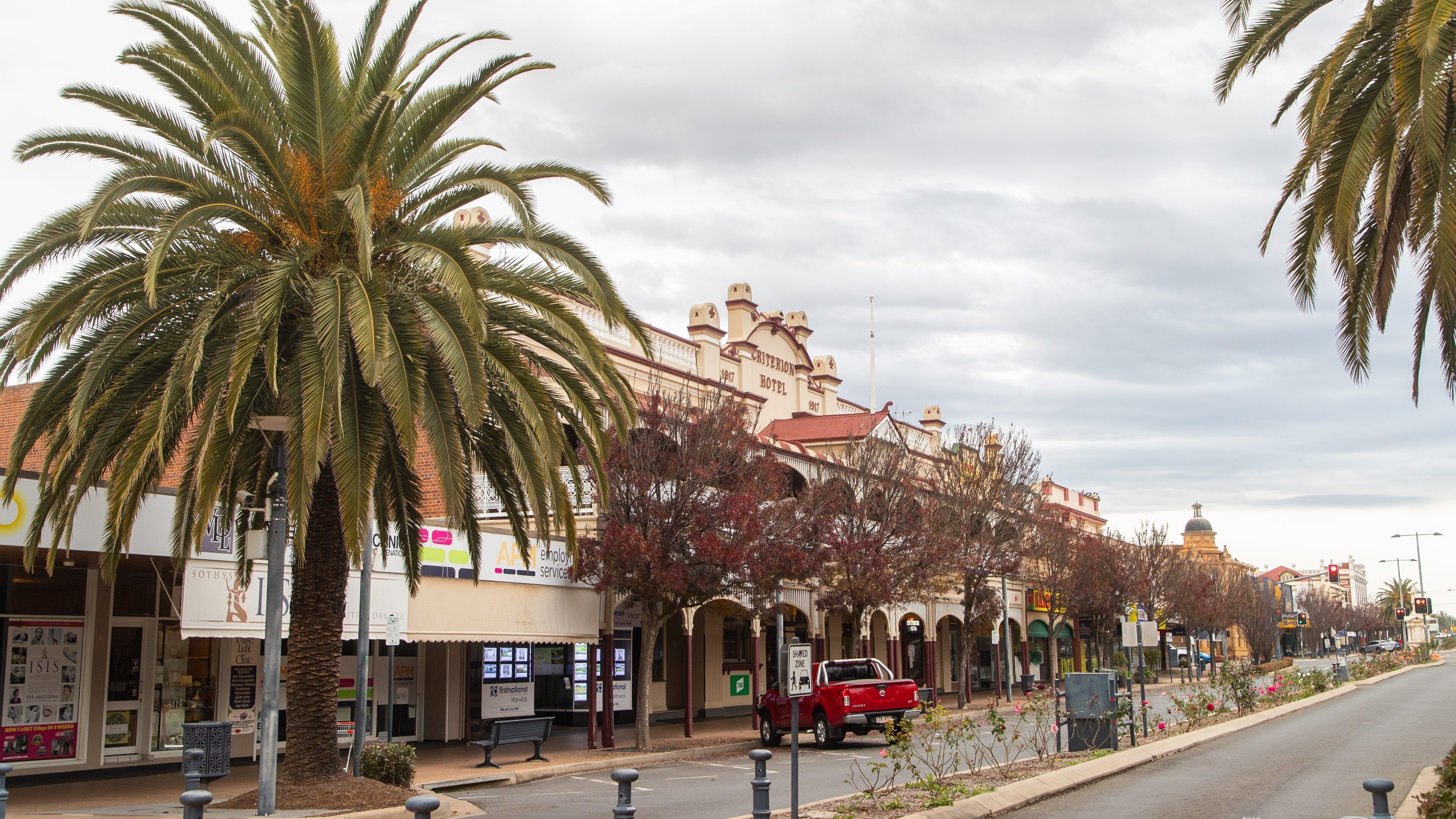 A street with palm trees, a red truck, and a building labeled 'Criterion Hotel'.