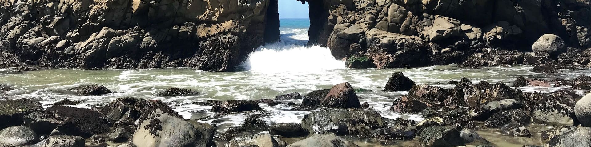 A rugged coastal rock formation with a natural archway.