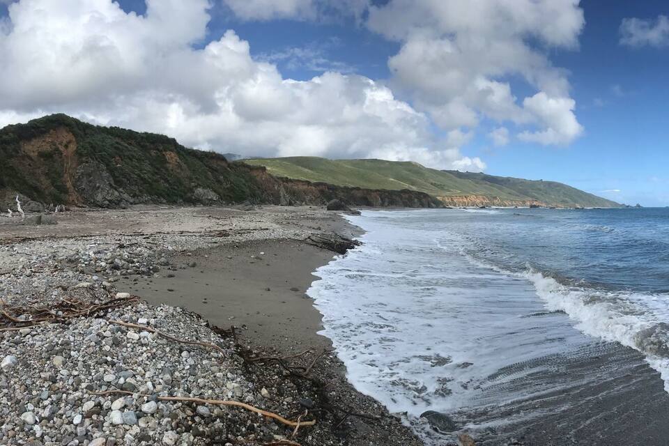 Ein Strand mit Wellen, felsigem Ufer und Klippen.