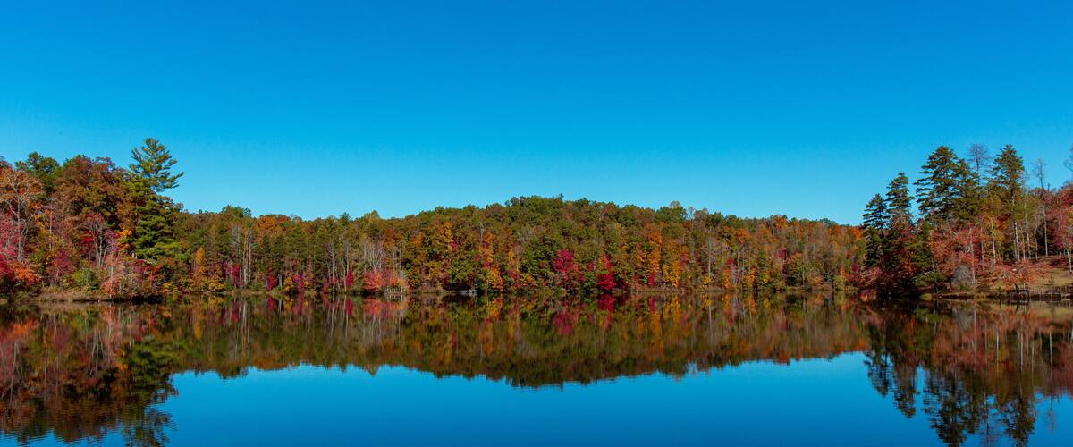 A calm lake reflecting autumn trees.