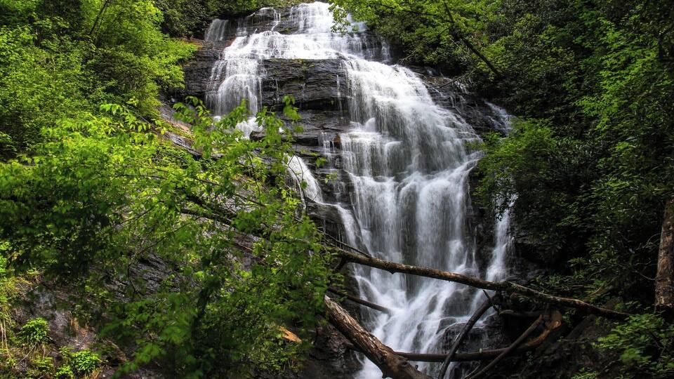 A waterfall cascading over a rocky cliff surrounded by lush green foliage.