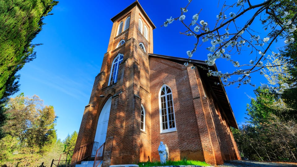 A brick church with a tall tower and arched entrance.