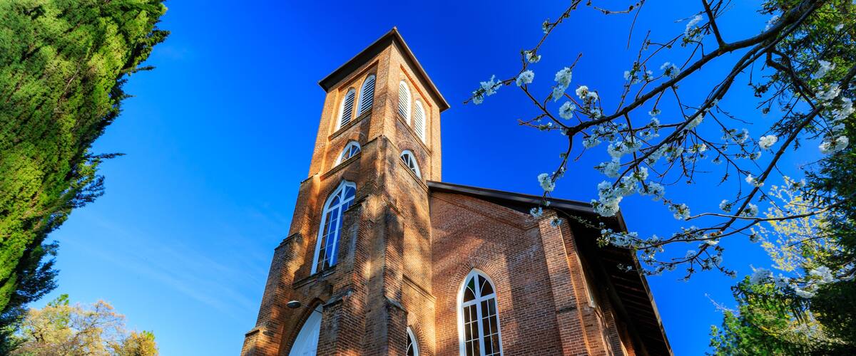 A brick church with a tall tower and arched entrance.