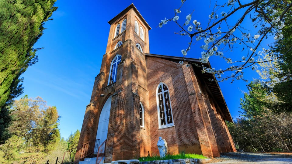 A brick church with a tall tower and arched windows.
