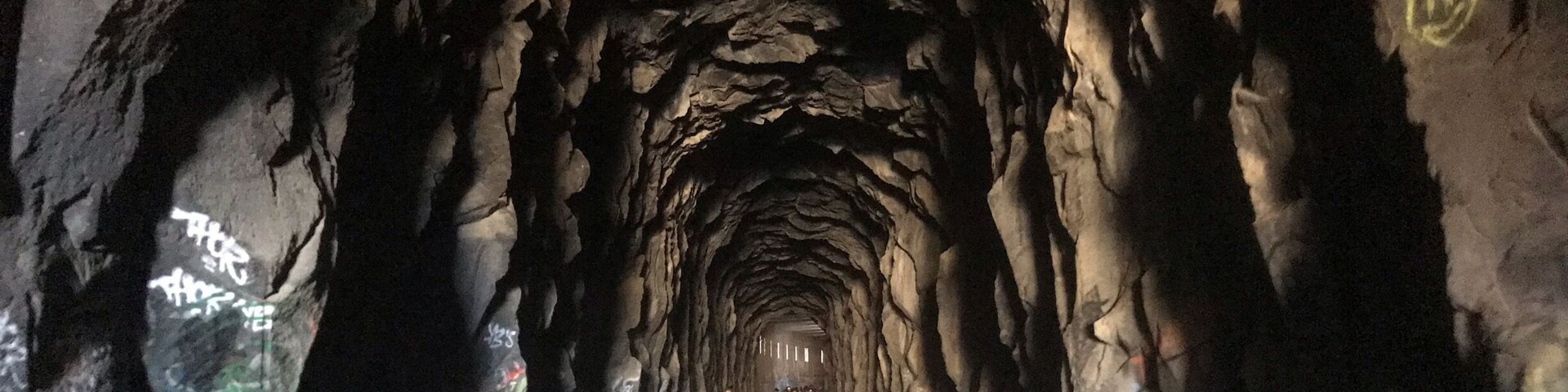 Un túnel con paredes rugosas e irregulares, con grafitis.