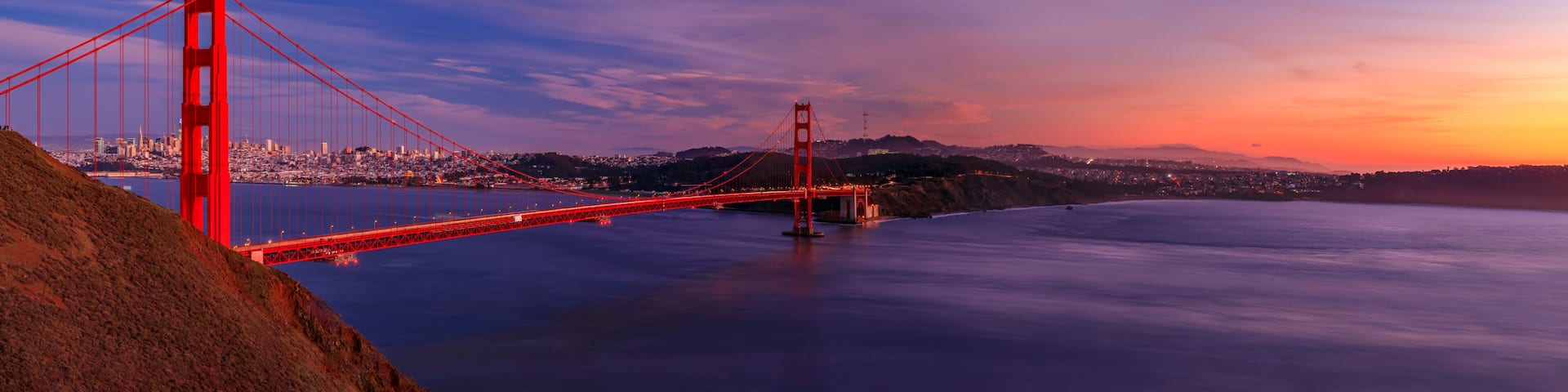Panorama of the Golden Gate bridge with the Marin Headlands and San Francisco skyline at colorful sunset, California