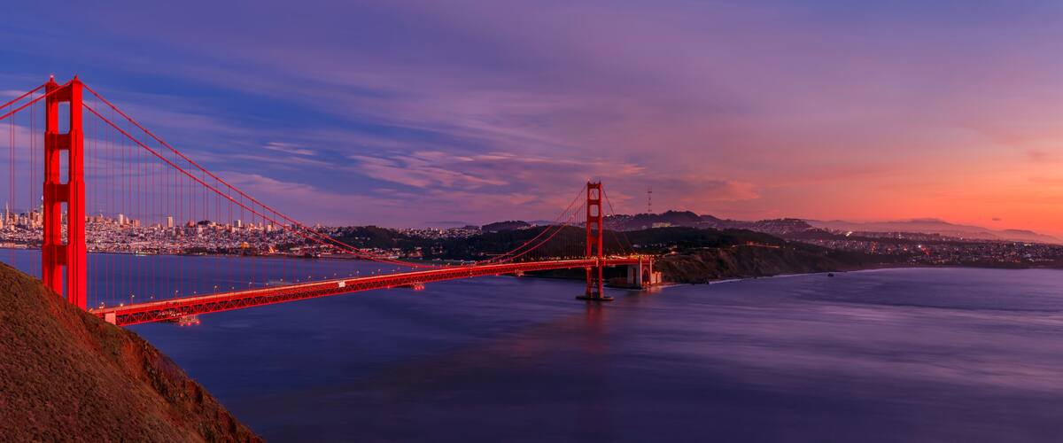 The Golden Gate Bridge at sunset with a cityscape in the background.
