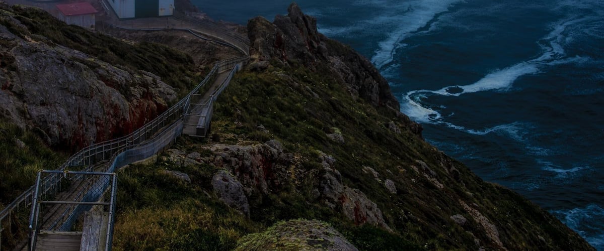 Un phare situé sur la côte et un escalier en bois menant à la mer.