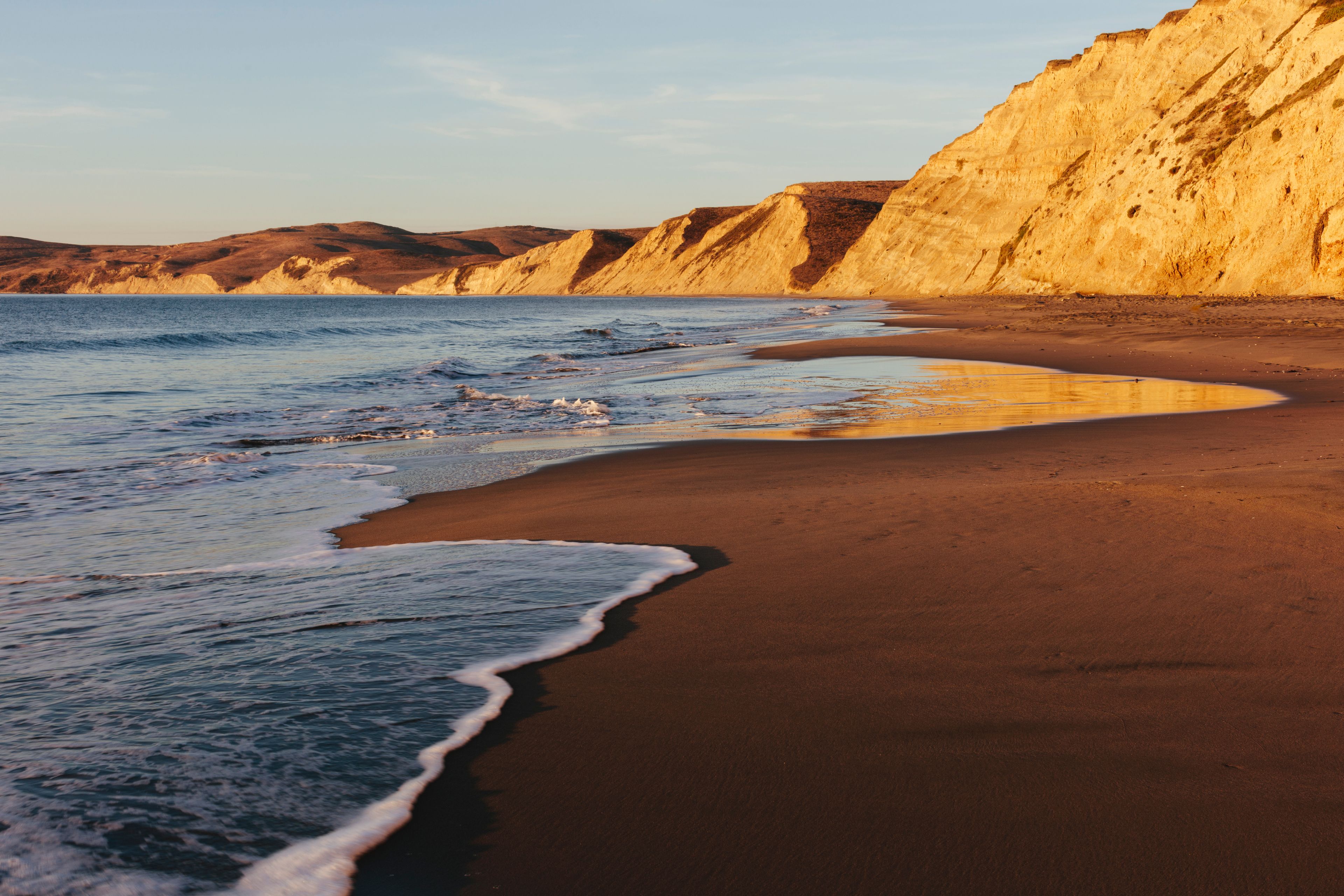 Beach at dawn, with sheer cliffs and rocks.  ,Drakes Beach, Point Reyes National Seashore
