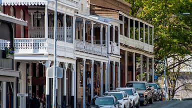 Uma rua repleta de edifícios históricos, carros estacionados e uma placa indicando 'SPANISH ST'.