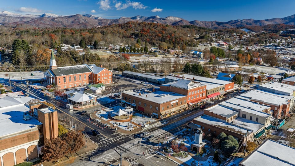 A town with a prominent church, a roundabout, and a mountainous backdrop.