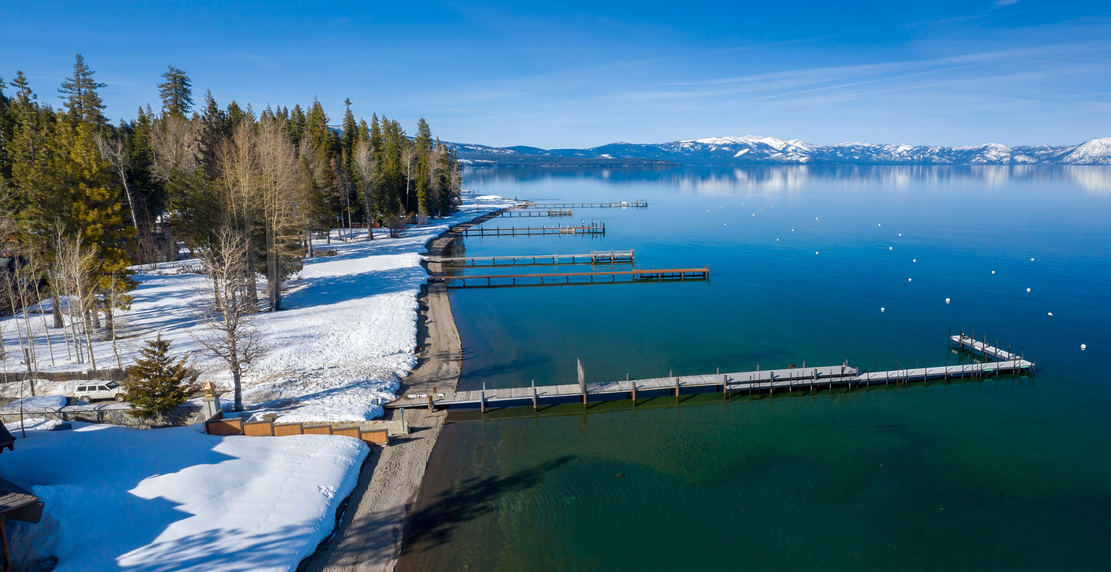 Pier, mountains with snow on calm Lake Tahoe, Homewood, California, United States of America.