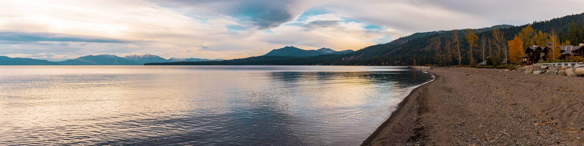 Panoramic sunset view of the shore, the dock and the hill full of pines in Lake Tahoe