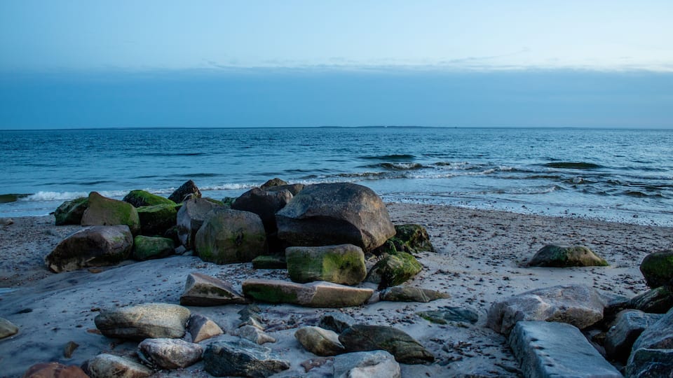 A rocky beach with large boulders and the ocean in the background.