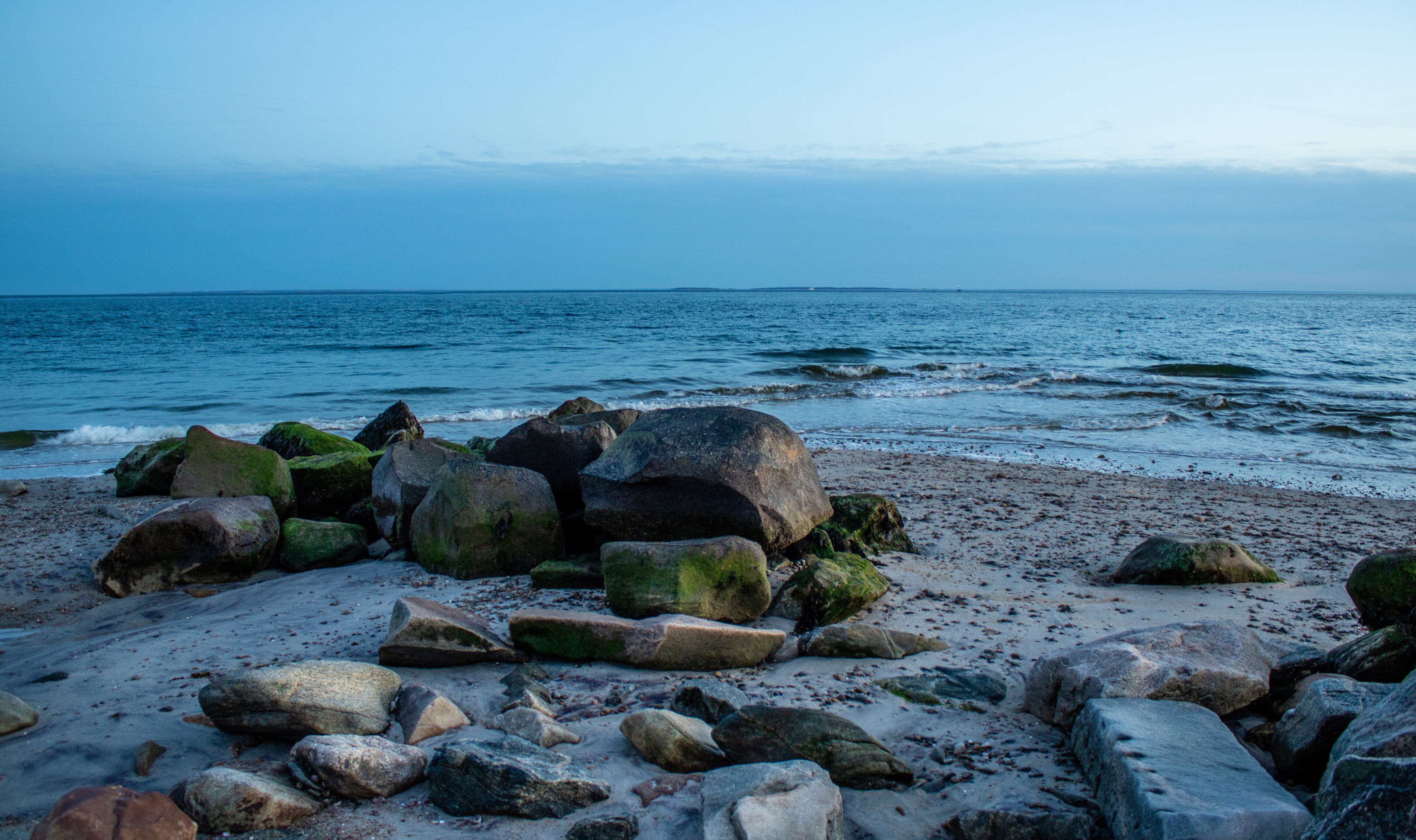 A rocky beach with large boulders and the ocean in the background.