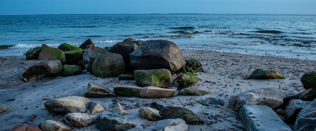 A rocky beach with large boulders and the ocean in the background.