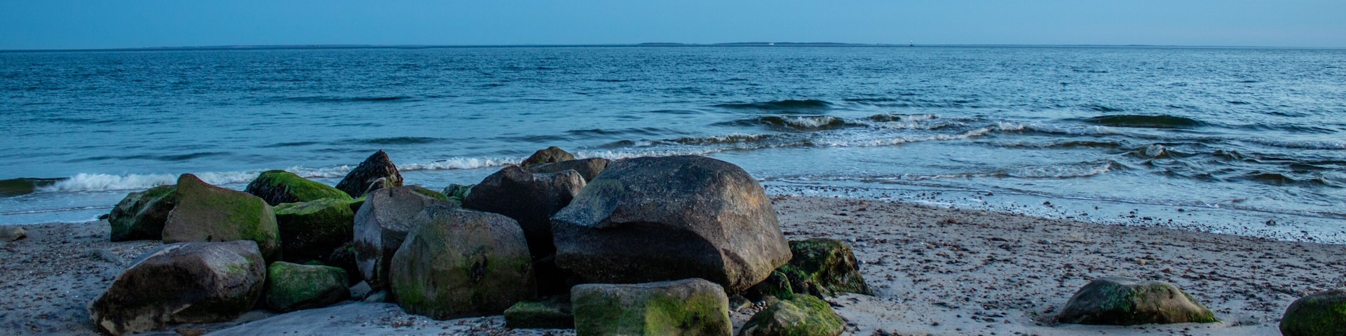 A rocky beach with large boulders and the ocean in the background.