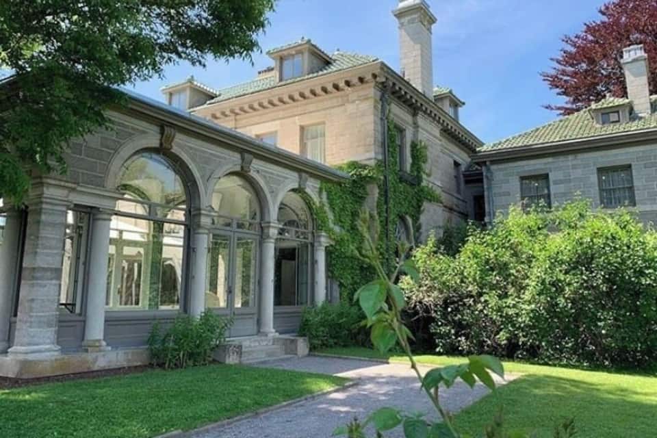 A classical building with arched windows and a well-maintained lawn.