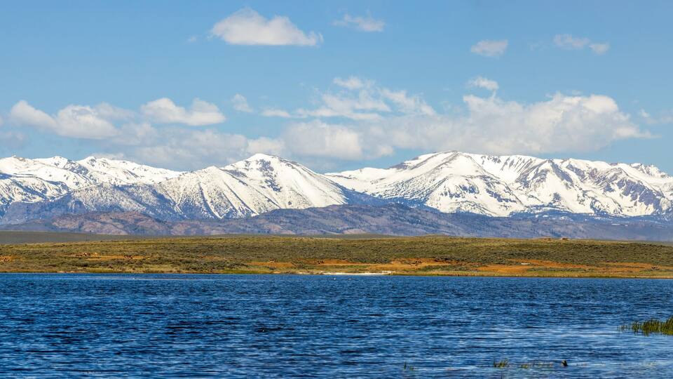 A lake with snow-capped mountains in the background.