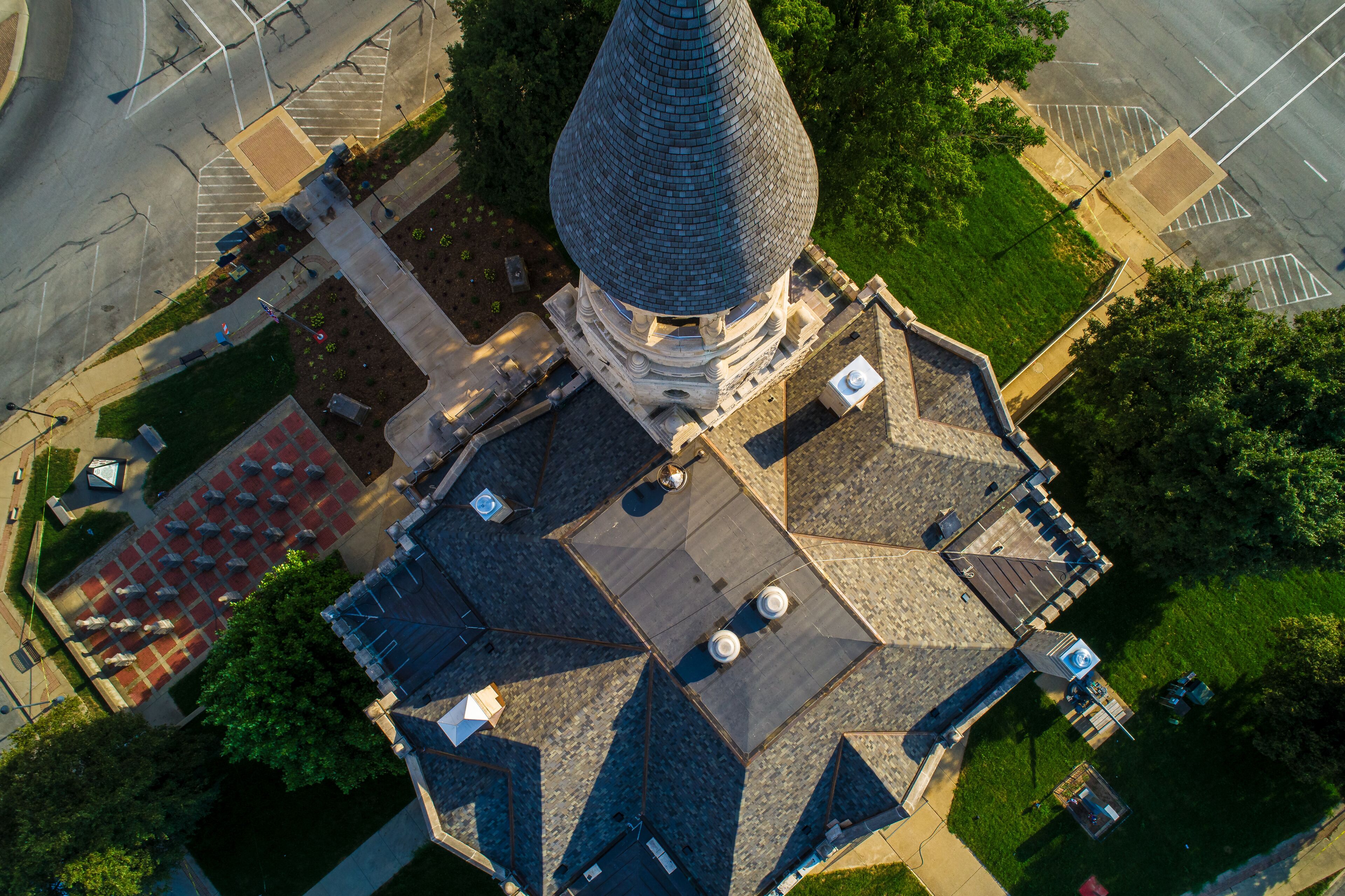 An aerial view of a unique building with a conical roof, surrounded by a parking lot and greenery.