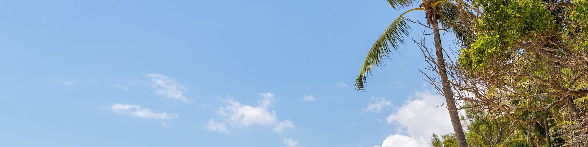 A sandy beach with gentle waves, a clear blue sky, and a mountain in the distance.