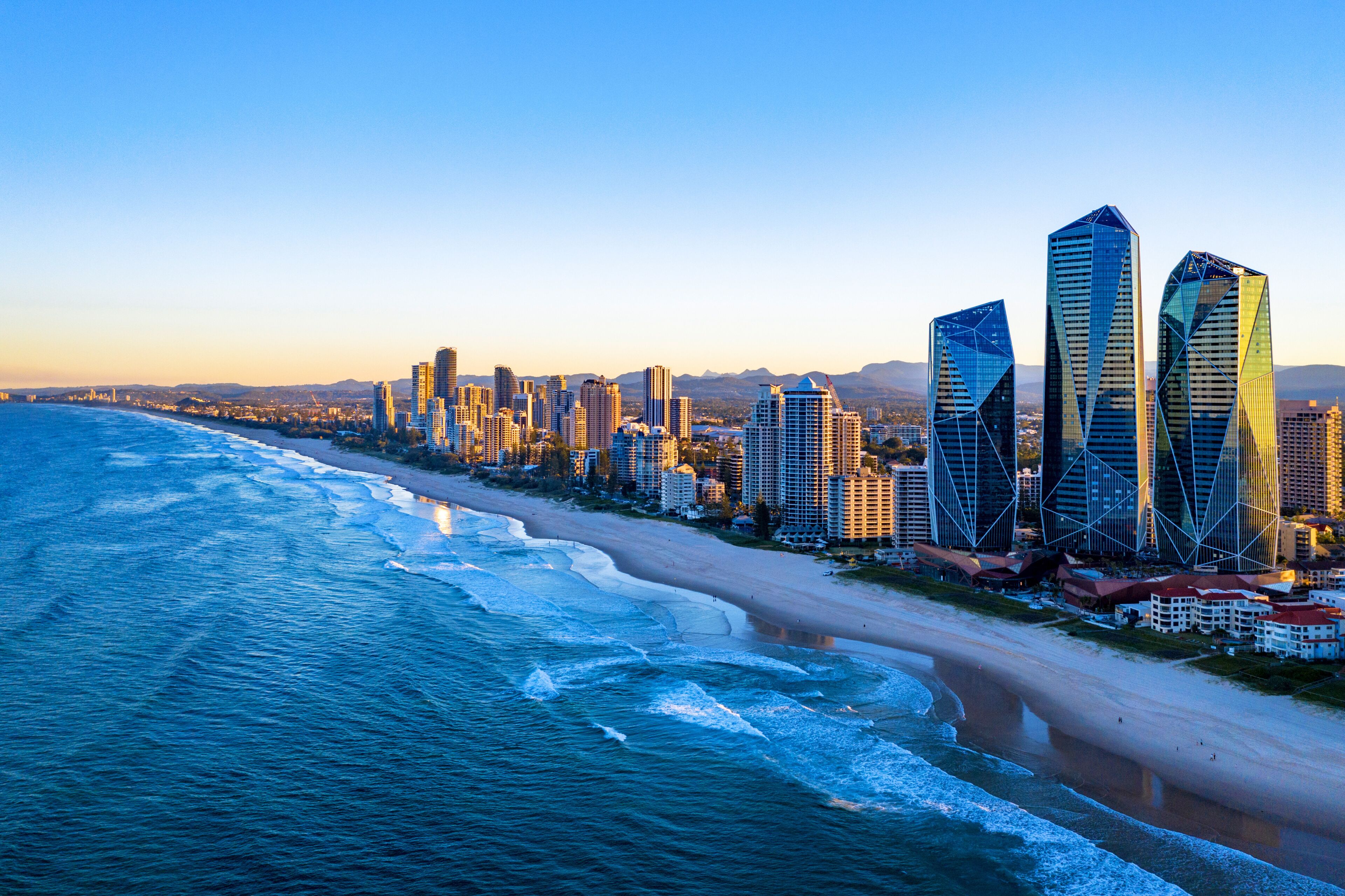 Un paisaje urbano costero con playa, océano y rascacielos modernos.