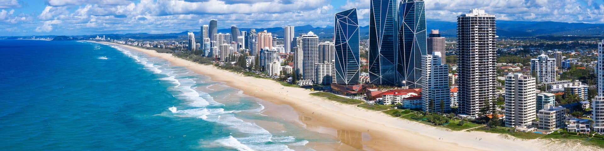 A coastal cityscape with a beach, ocean, and modern skyscrapers.