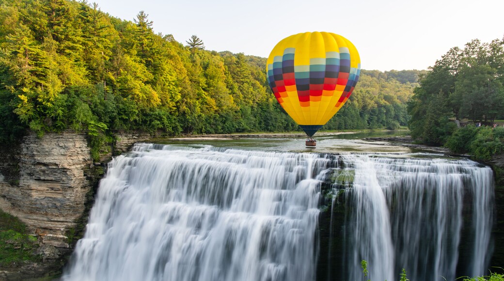 Una cascada con un globo aerostático al fondo.