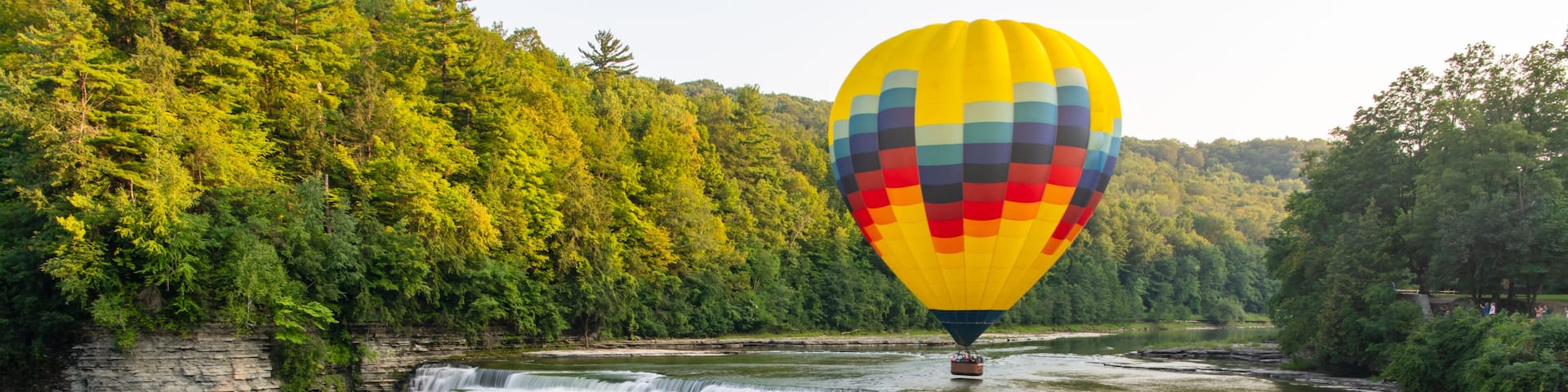 A waterfall with a hot air balloon in the background.