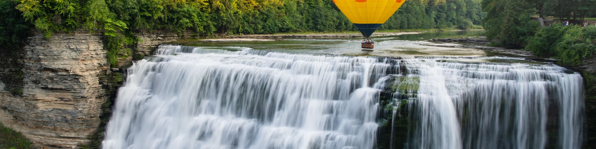 A waterfall with a hot air balloon in the background.
