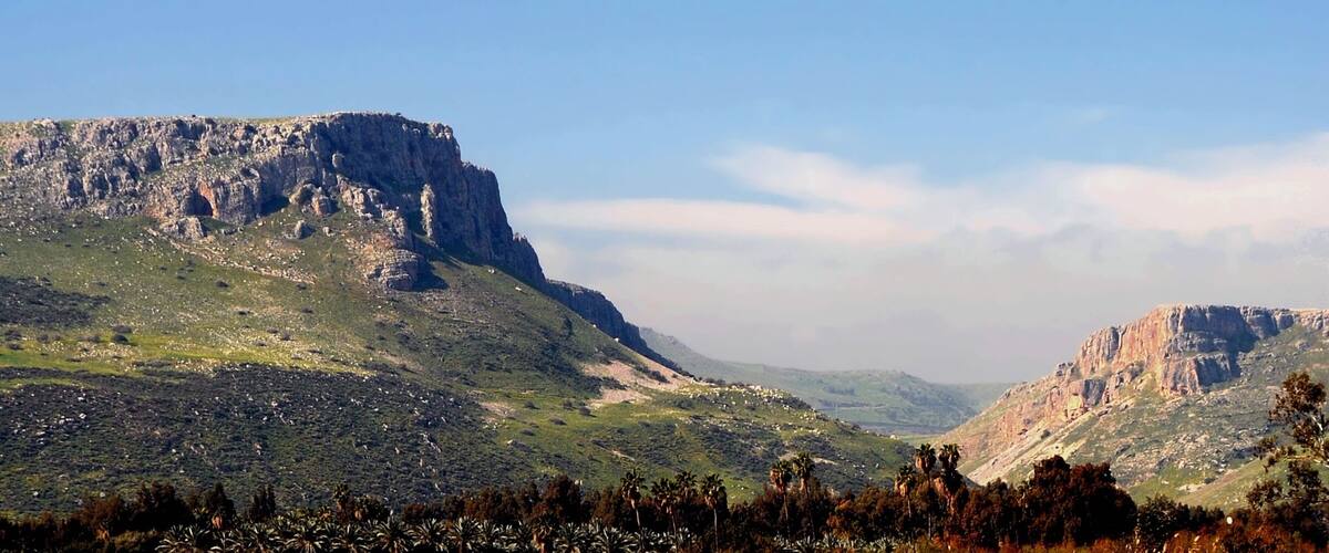 A mountainous landscape with rocky cliffs and sparse vegetation.
