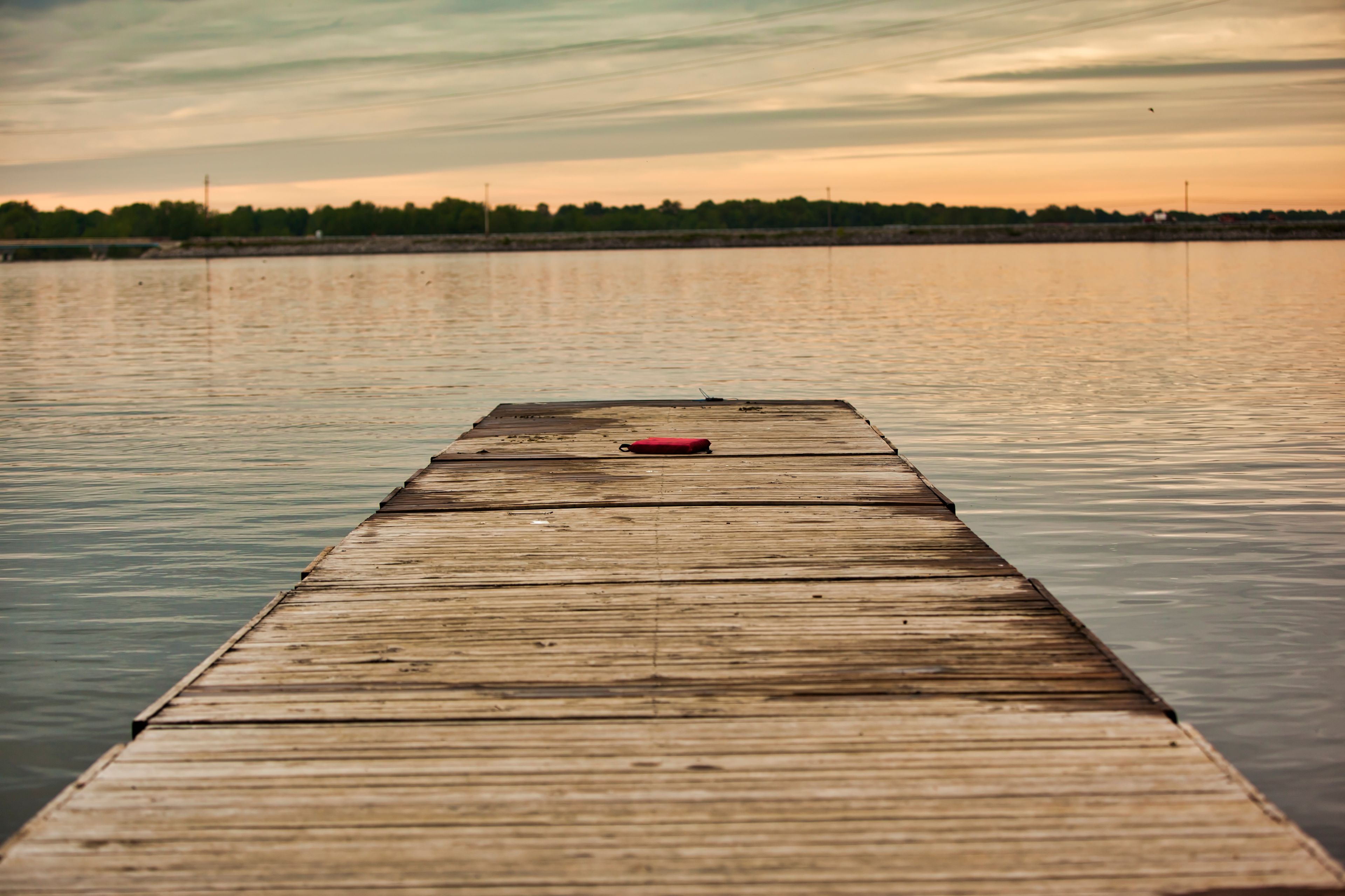 A wooden pier extending into calm water with a sunset sky.
