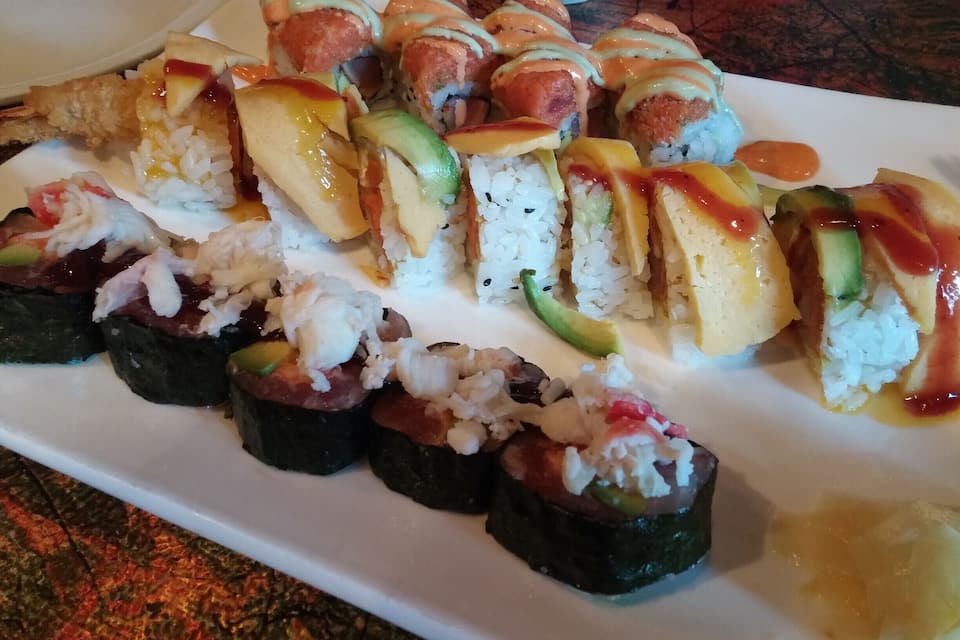 Um prato de sushi com diversos acompanhamentos e molhos.