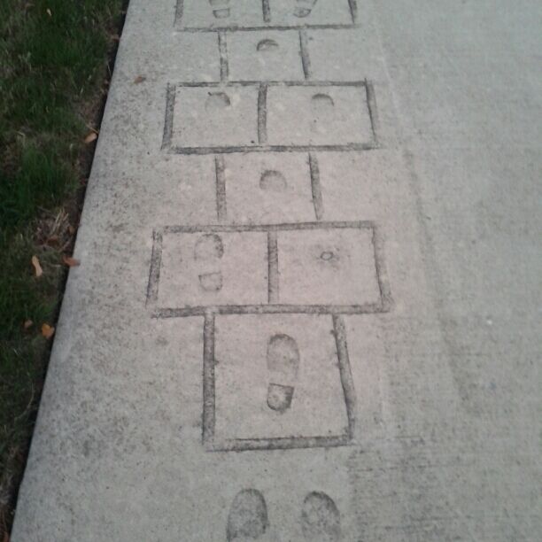 A hopscotch game etched into the concrete. A part of the activities walkway with various physical activities expressed as impressions in the concrete.