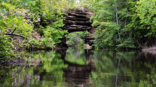 Tennessee Panorama. Natural arch formation surrounded by beautiful mountain laurel reflected in a lake. Pickett State Park.