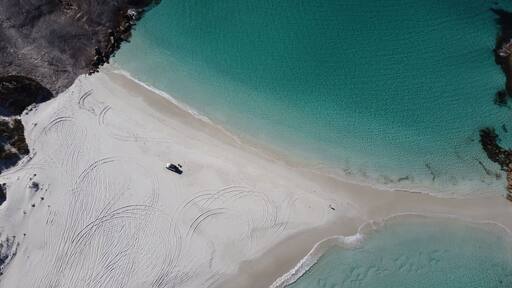 Aerial picture of Wylie bay in Esperance. Car parked on the beach. Blue and shallow water. Very beautiful and calm landscape. Driving on the sand in Australia.