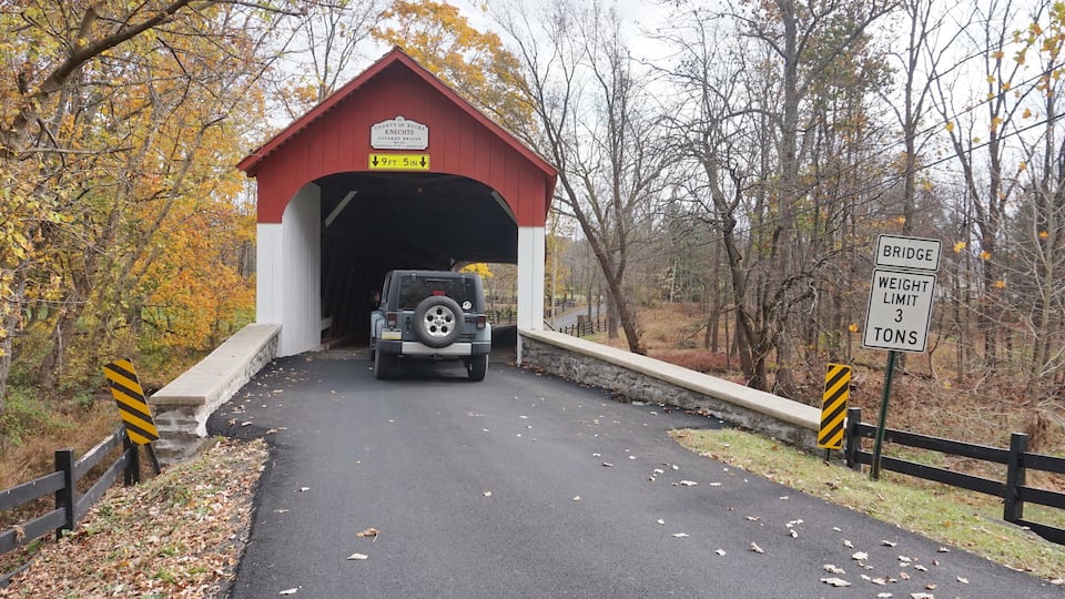A covered bridge with a weight limit sign and a vehicle approaching.