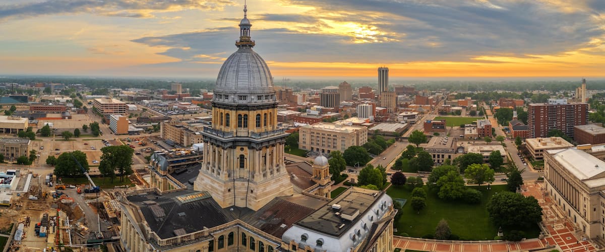 A cityscape with a prominent dome building, a tall tower, and a sunset sky.