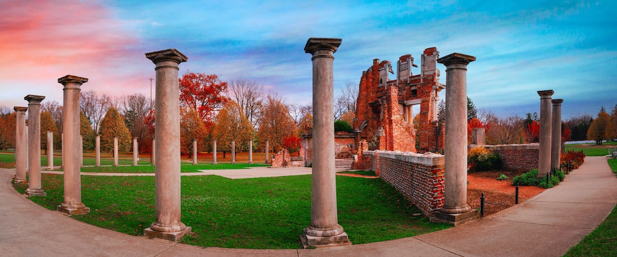 Ancient columns, a brick structure, and autumn trees.