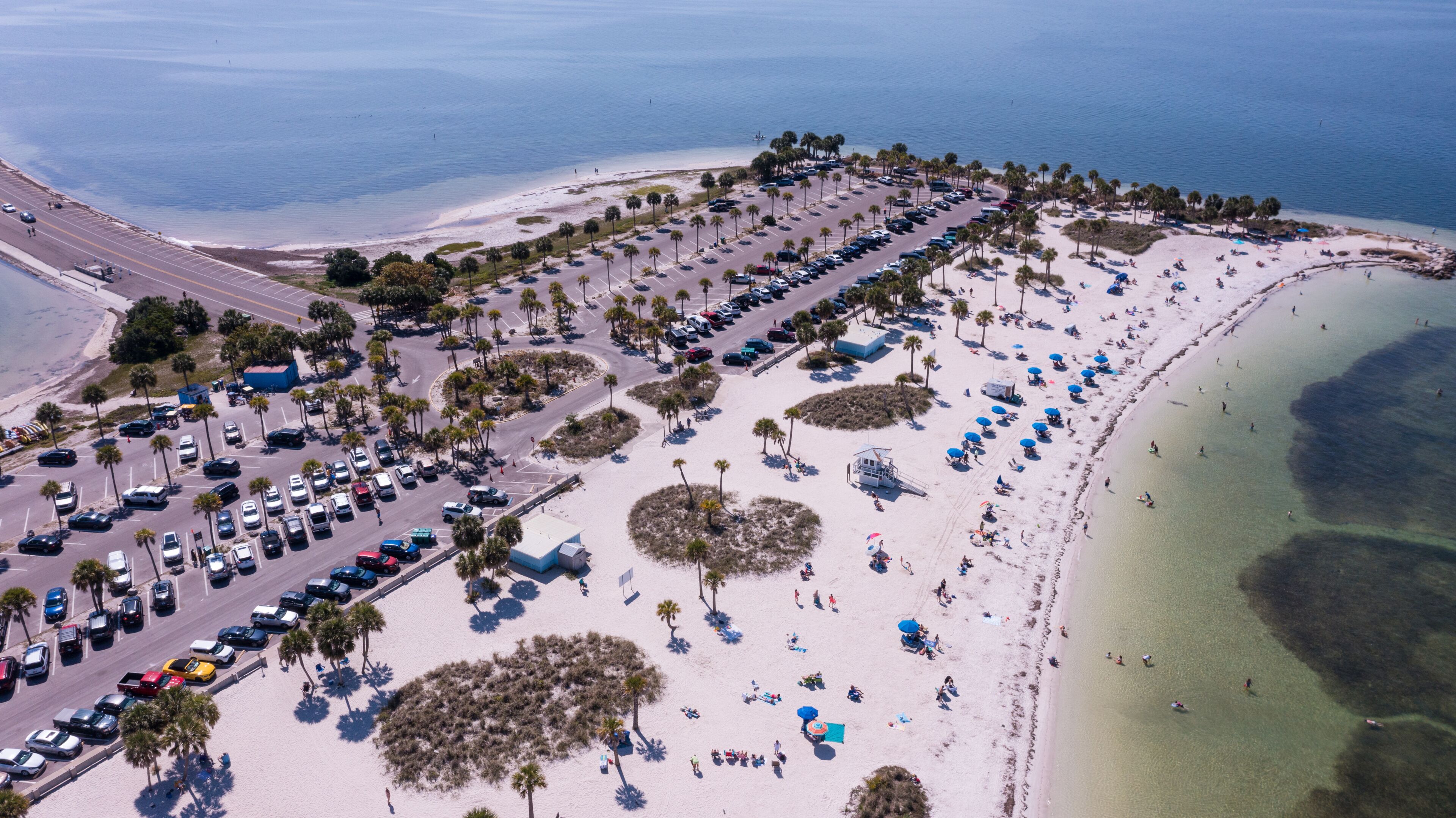 An aerial view of a coastal area with a parking lot, beach, and ocean.