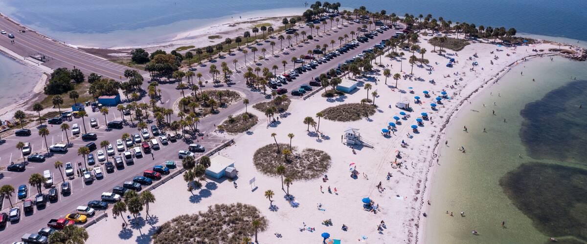 An aerial view of a coastal area with a parking lot, beach, and ocean.