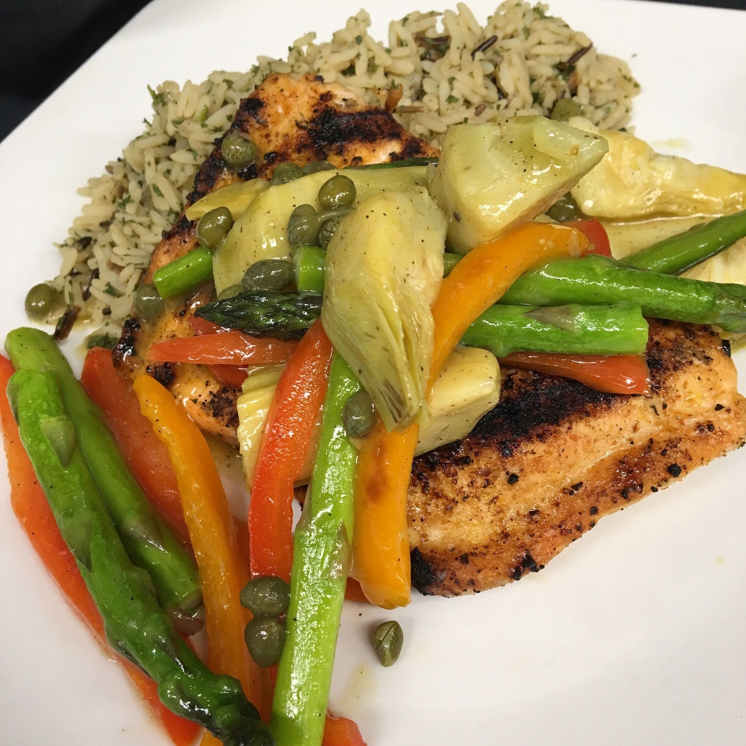 Mediterranean Grilled Salmon topped with asparagus, peppers capers and artichoke served over wild rice. #GoodEats